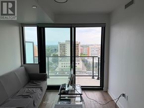 Mississauga (Cooksville) condo for rent - A living room with a grey sofa and a table with a laptop on it.