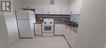 Toronto (Elms-Old Rexdale) condo for rent - A white refrigerator is in a kitchen with white cabinets.