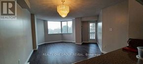 Toronto (Elms-Old Rexdale) condo for rent - A large, empty room with a chandelier and a window overlooking a tree-covered landscape.