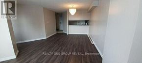 Toronto (Elms-Old Rexdale) condo for rent - A large empty room with a wooden floor and a chandelier hanging from the ceiling.