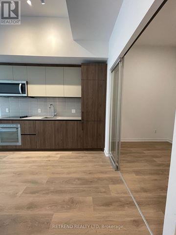 Toronto (South Riverdale) condo for rent - A kitchen with wooden cabinets and a microwave above the stove.
