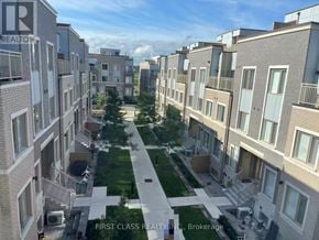 Vaughan (Vaughan Corporate Centre) townhouse for rent - A view of a residential area with apartment buildings and a green lawn in the foreground.