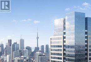Toronto (North St. James Town) condo for rent - A cityscape with a tall building in the foreground and the CN Tower in the background.