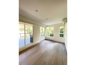 Surrey apartment for rent - A spacious room with wooden floors and large windows.