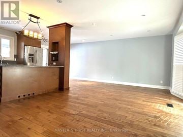 Burlington (Appleby) apartment for rent - A room with a wooden floor and a kitchen area with a refrigerator, sink and cabinets.