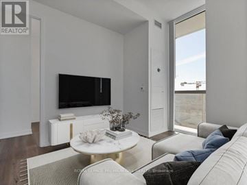 Vaughan (Vaughan Corporate Centre) condo for rent - A living room with a white couch and a flat screen TV mounted on the wall.