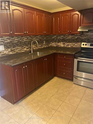 Mississauga (Hurontario) apartment for rent - A kitchen with brown cabinets and a tiled backsplash.