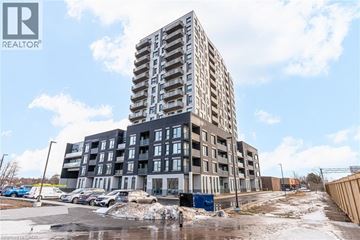 Kitchener condo for rent - A tall building with a parking lot in front of it.