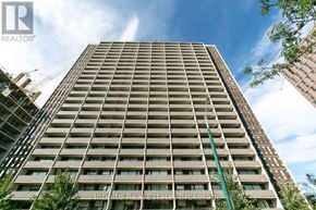 Toronto (University) condo for rent - A tall residential building with a crane in the background.
