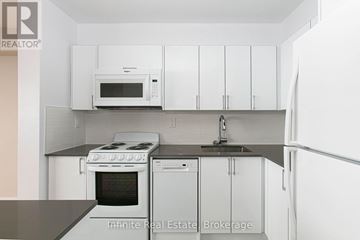 Toronto (University) condo for rent - A kitchen with white cabinets and a black counter top.