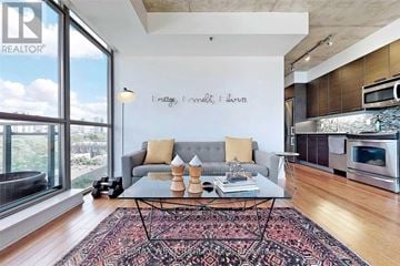 Toronto (Moss Park) condo for rent - A living room with a grey couch and a coffee table in front of a window.