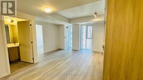Toronto (Waterfront Communities) condo for rent - A spacious room with wooden flooring and white walls, with a doorway leading to another room.