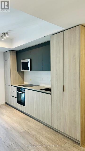Toronto (Waterfront Communities) condo for rent - A modern kitchen with wooden cabinets and a microwave above the stove.