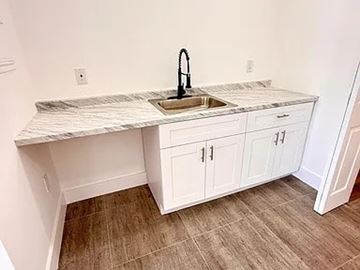 Miami Beach apartment for rent - A kitchen with a marble countertop and white cabinets.