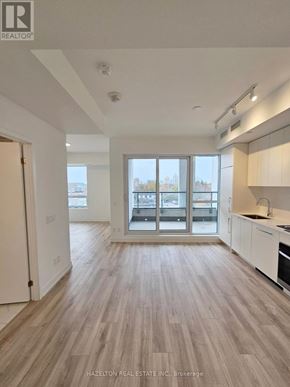 Toronto (Willowdale East) condo for rent - A real estate listing photo of a kitchen and living room with wood floors and white walls.