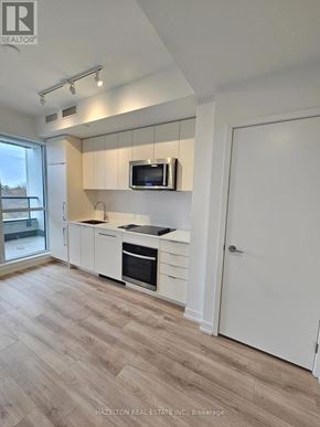 Toronto (Willowdale East) condo for rent - A kitchen with white cabinets and a microwave above the oven.