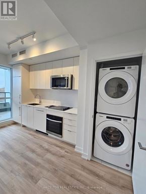 Toronto (Willowdale East) condo for rent - A modern kitchen with a washer and dryer built into the cabinetry.