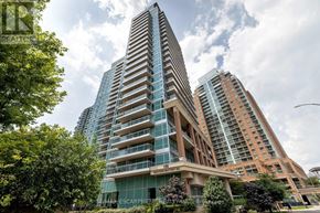 Toronto (Niagara) condo for rent - A tall building with a glass facade stands in front of a tree.
