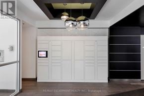 Toronto (Niagara) condo for rent - A white kitchen with a black fridge and a black and white cabinet.