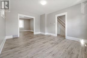 Thorold (Thorold Downtown) multi-family for rent - A spacious room with wooden flooring and white walls, featuring a staircase with a railing.