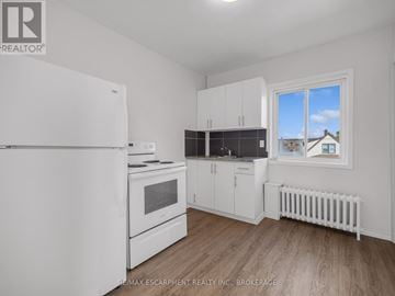 Thorold (Thorold Downtown) apartment for rent - A white refrigerator is in a kitchen with wood floors and white walls.