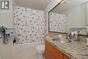 Coquitlam apartment for rent - A bathroom with a white toilet, a sink, and a shower curtain with butterflies on it.