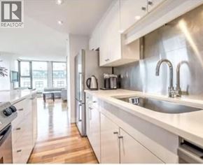 Vancouver apartment for rent - A modern kitchen with white cabinets and stainless steel appliances.