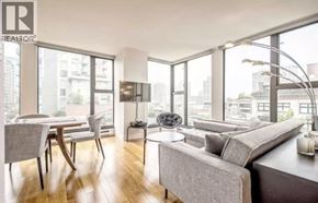 Vancouver apartment for rent - A living room with a grey couch and a dining table with chairs.