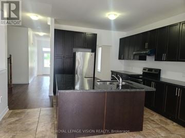 Oshawa (Samac) apartment for rent - A kitchen with a black counter and a stainless steel refrigerator.