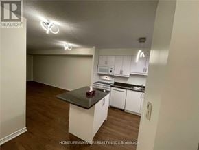 Mississauga (City Centre) condo for rent - A kitchen with white cabinets and a black countertop.