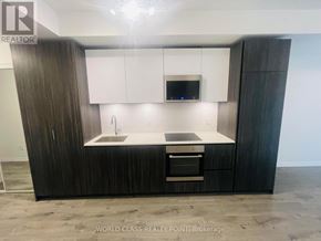 Toronto (Waterfront Communities) condo for rent - A modern kitchen with dark wood cabinets and a white countertop.