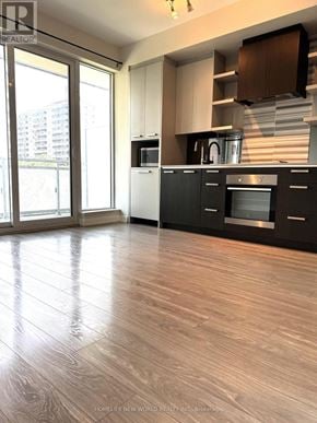 Toronto (High Park North) condo for rent - A modern kitchen with wooden flooring and black cabinets.