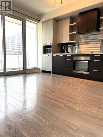 Toronto (High Park North) condo for rent - A modern kitchen with wooden flooring and black cabinets.