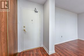 Burlington (Brant Hills) condo for rent - A white door with a gold handle is in a room with wood flooring.