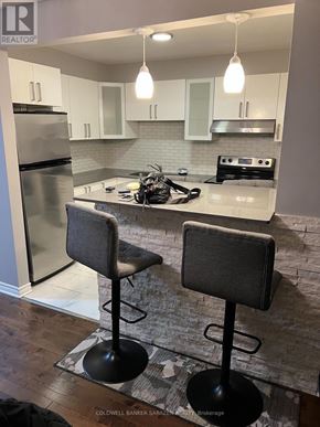Ottawa townhouse for rent - A kitchen with a refrigerator, stove, and bar stools.