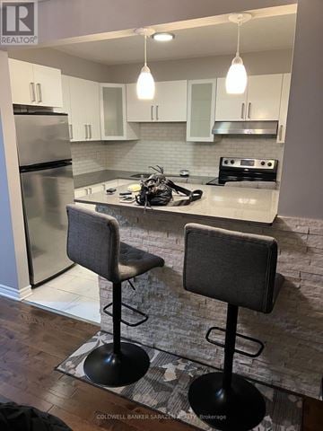 Ottawa townhouse for rent - A kitchen with a refrigerator, stove, and bar stools.