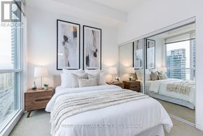 Toronto (Waterfront Communities) condo for rent - A bedroom with a large bed, two nightstands, and a large window.