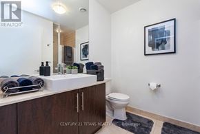 Toronto (Waterfront Communities) condo for rent - A bathroom with a toilet, sink, and mirror.