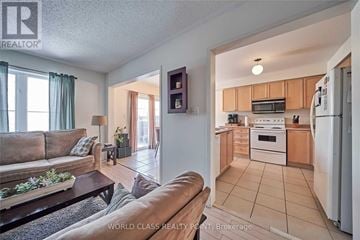 Ajax (Northeast Ajax) apartment for rent - A living room with a couch and a kitchen area in the background.