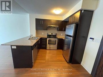 Markham (Commerce Valley) condo for rent - A kitchen with black cabinets and a stainless steel refrigerator.