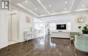 Brampton (Northwest Brampton) apartment for rent - A spacious living room with a television, white furniture, and a large mirror on the wall.