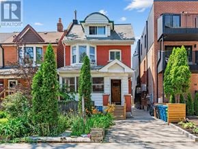 Toronto (Dovercourt-Wallace Emerson-Junction) apartment for rent - A house with a red brick wall and a white house with a black roof.