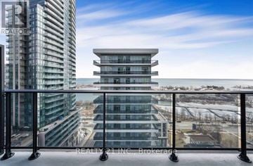 Toronto (Mimico) condo for rent - A modern glass building with a balcony overlooking a snowy landscape.