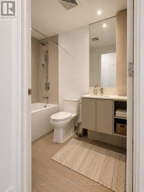Mississauga (City Centre) condo for rent - A white toilet is in a bathroom with a white tub and a white sink.