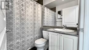 Mississauga (City Centre) condo for rent - A white toilet sits in a bathroom with a patterned wallpaper.