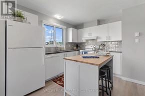 Ottawa condo for rent - A kitchen with white appliances and cabinets, a wooden island, and a rug on the floor.