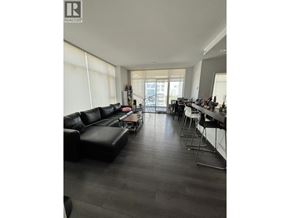 Burnaby apartment for rent - A living room with a black couch and a dining table.