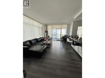 Burnaby apartment for rent - A living room with a black couch and a dining table.