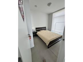 Burnaby apartment for rent - A bedroom with a bed, nightstand, and window.