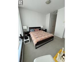 Burnaby apartment for rent - A bedroom with a bed, nightstand, and a small table with a lamp.